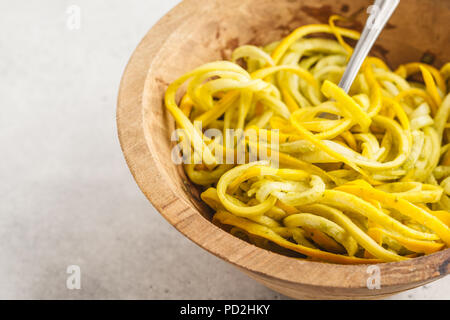 Raw vegan Zucchini Nudeln in eine hölzerne Schüssel. Gesunde Rohstoffe veganes Essen Konzept. Stockfoto