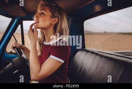 Frau Blick in den Rückspiegel beim Fahren ein Auto. Schöne Frau auf einem Road Trip. Stockfoto