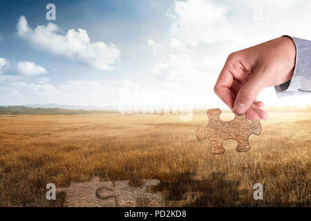 Hände halten Puzzleteil auf dem goldenen Feld. Ernte im Herbst Konzept Stockfoto