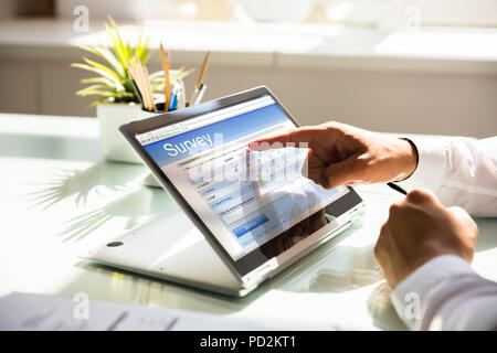 Nahaufnahme der Hand ein Geschäftsmann füllen online Umfrage Formular auf Laptop im Büro Stockfoto