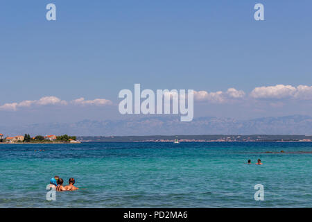 Zadar, Kroatien - 24. Juli 2018: Menschen schwimmen im transparenten Gewässern der Insel Ugljan Stockfoto