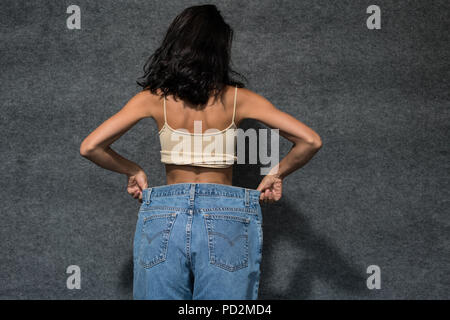 Körper eines schlanken Mädchen mit enormen Jeans, isoliert auf weißem Stockfoto