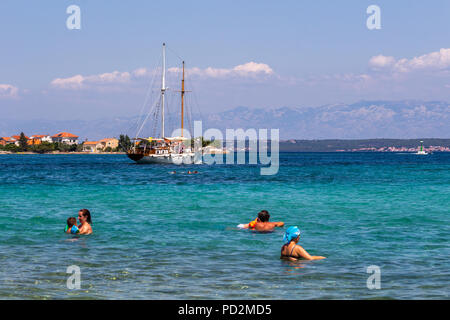 Zadar, Kroatien - 24. Juli 2018: Menschen schwimmen im transparenten Gewässern der Insel Ugljan Stockfoto