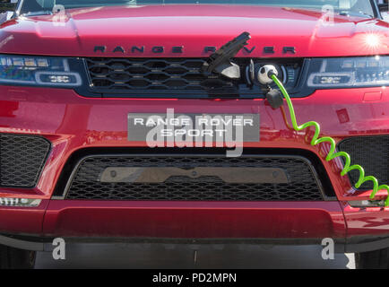 Ein elektrisch angetriebenes Auto Range Rover an eine Ladegerät Power und auftanken in einer umweltfreundlichen Art und Weise zu ergänzen. elektrisch angetriebene Fahrzeuge Stockfoto