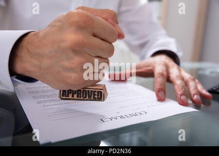 Der Geschäftsmann Hand Stanzen Genehmigt auf Vertrag Papier mit Stamper Stockfoto