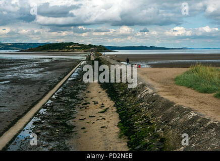 Menschen zu Fuß auf Gezeiten Causeway in Cramond Insel mit dem Zweiten Weltkrieg anti Schiff Barriere mit Resten von verschlissenen Betonmasten, Edinburgh, Schottland, Großbritannien Stockfoto