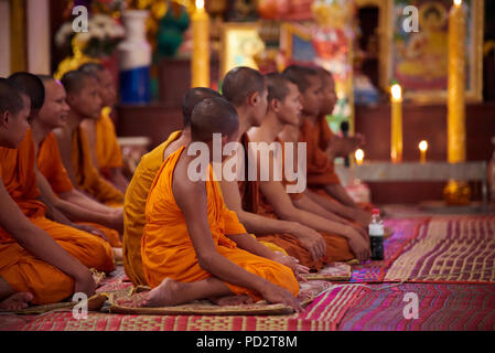 Eine Gruppe Junge buddhistische Mönche auf dem Boden sitzend während einer Zeremonie in einem der Schreine in ihrem Kloster. In Siem Reap, Kambodscha. Stockfoto