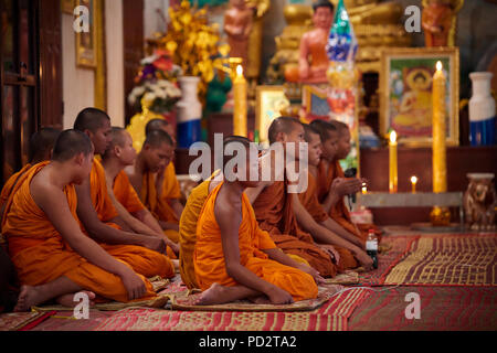 Eine Gruppe Junge buddhistische Mönche auf dem Boden sitzend während einer Zeremonie in einem der Schreine in ihrem Kloster. In Siem Reap, Kambodscha. Stockfoto