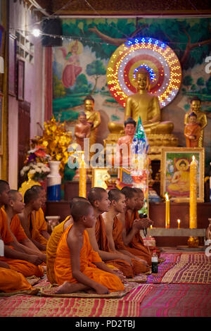 Eine Gruppe Junge buddhistische Mönche auf dem Boden sitzend während einer Zeremonie in einem der Schreine in ihrem Kloster. In Siem Reap, Kambodscha. Stockfoto