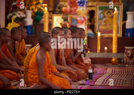 Eine Gruppe Junge buddhistische Mönche auf dem Boden sitzend während einer Zeremonie in einem der Schreine in ihrem Kloster. In Siem Reap, Kambodscha. Stockfoto