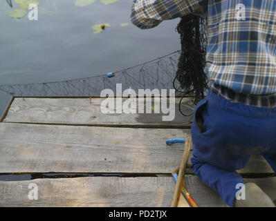 Disabeld Mann auf die Knie und Fischen mit Netz, verschwommene Bewegung geschossen Stockfoto