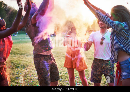 Fünf junge erwachsene Freunde tanzen und werfen farbige Kreide Pulver im Holi Festival Stockfoto