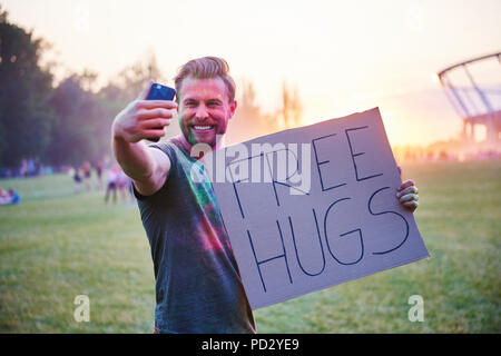 Junger Mann unter selfie Holding Free hugs Zeichen im Holi Festival Stockfoto