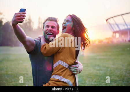 Junges Paar in farbige Kreide Pulver unter selfie im Holi Festival abgedeckt Stockfoto