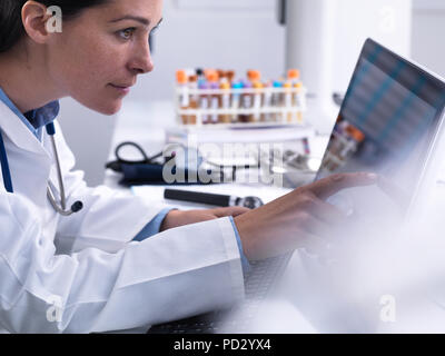 Arzt Zugriff auf einen Patienten details über einen Touch screen Computer in der Klinik Stockfoto