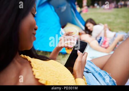 Frau mit Handys an Music Festival, Freunde im Hintergrund Stockfoto