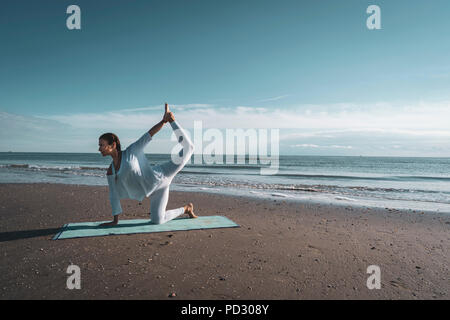 Frau praktizieren Yoga am Strand Stockfoto