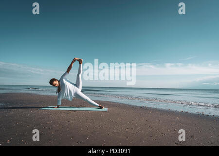 Frau praktizieren Yoga am Strand Stockfoto