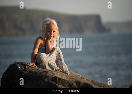 Porträt der jungen Mädchen, sitzen auf den Felsen, Doolin, Clare, Irland Stockfoto