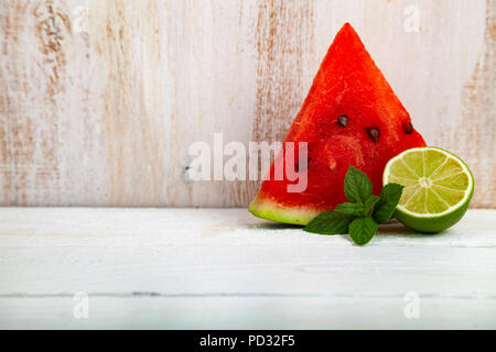 Stücke von Wassermelone, Limette und Minze auf einen hölzernen Tisch. Köstliches Dessert. Stockfoto