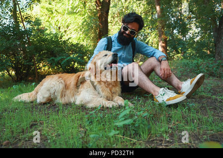 Mann mit Bart und seinen kleinen gelben Hund spielen und genießen Sonne Stockfoto