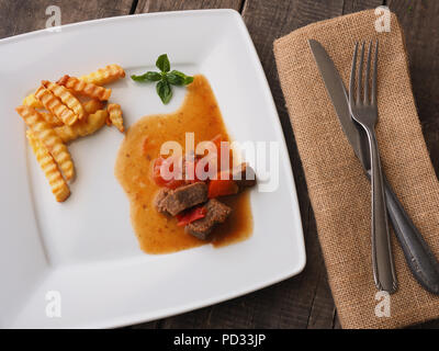 Lecker Gulasch von organischem Rindfleisch mit Pommes frites auf einer weißen Platte Stockfoto