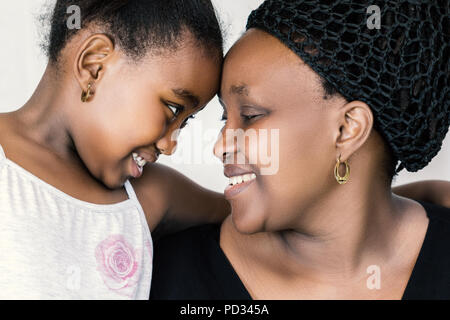 Nahaufnahme Gesicht schoss der afrikanischen Mutter und Tochter an jedem anderen suchen. Ausschreibung Nahaufnahme Portrait von Kid Kopf mit Mutter gegen Weiße isoliert Stockfoto