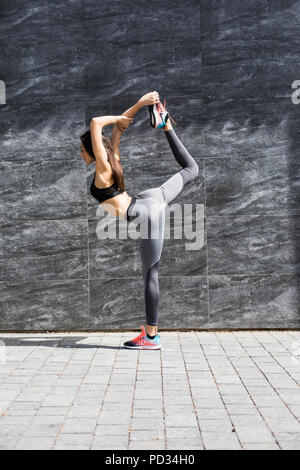 Junge fitness Frau tun, Warm-up-Training bevor sie ihr Bein ausdehnen, indem sie Knie zur Brust Strecke auf der Straße der Stadt. Sportliche Athlet pr Stockfoto