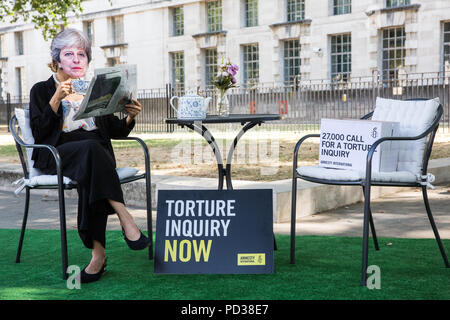 London, Großbritannien. 6. August 2018. Ein Aktivist von Amnesty International UK das Tragen eines Theresa May Maske Getränke Tee Außerhalb der Downing Street und ignoriert Opfer von Folter als Teil einer Protestbewegung, die für eine unabhängige, Richter - LED-Anfrage in Einbeziehung des Vereinigten Königreichs in die Folter von Gefangenen in Übersee. Eine Petition wurde auch an 10 Downing Street von Amnesty Kate Allen, Direktor der britischen, Simone Abel von Reprieve, Sam Grant der Freiheit und Sonya Sceats der Freiheit von Folter dargestellt). Credit: Mark Kerrison/Alamy leben Nachrichten Stockfoto