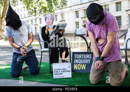 London, Großbritannien. 6. August 2018. Ein Aktivist von Amnesty International UK das Tragen eines Theresa May Maske Getränke Tee Außerhalb der Downing Street und ignoriert Opfer von Folter als Teil einer Protestbewegung, die für eine unabhängige, Richter - LED-Anfrage in Einbeziehung des Vereinigten Königreichs in die Folter von Gefangenen in Übersee. Eine Petition wurde auch an 10 Downing Street von Amnesty Kate Allen, Direktor der britischen, Simone Abel von Reprieve, Sam Grant der Freiheit und Sonya Sceats der Freiheit von Folter dargestellt). Credit: Mark Kerrison/Alamy leben Nachrichten Stockfoto