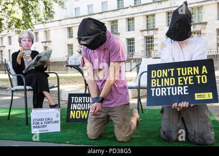 London, Großbritannien. 6. August 2018. Ein Aktivist von Amnesty International UK das Tragen eines Theresa May Maske Getränke Tee Außerhalb der Downing Street und ignoriert Opfer von Folter als Teil einer Protestbewegung, die für eine unabhängige, Richter - LED-Anfrage in Einbeziehung des Vereinigten Königreichs in die Folter von Gefangenen in Übersee. Eine Petition wurde auch an 10 Downing Street von Amnesty Kate Allen, Direktor der britischen, Simone Abel von Reprieve, Sam Grant der Freiheit und Sonya Sceats der Freiheit von Folter dargestellt). Credit: Mark Kerrison/Alamy leben Nachrichten Stockfoto