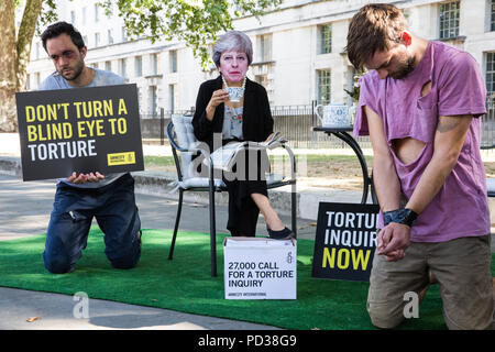 London, Großbritannien. 6. August 2018. Ein Aktivist von Amnesty International UK das Tragen eines Theresa May Maske Getränke Tee Außerhalb der Downing Street und ignoriert Opfer von Folter als Teil einer Protestbewegung, die für eine unabhängige, Richter - LED-Anfrage in Einbeziehung des Vereinigten Königreichs in die Folter von Gefangenen in Übersee. Eine Petition wurde auch an 10 Downing Street von Amnesty Kate Allen, Direktor der britischen, Simone Abel von Reprieve, Sam Grant der Freiheit und Sonya Sceats der Freiheit von Folter dargestellt). Credit: Mark Kerrison/Alamy leben Nachrichten Stockfoto