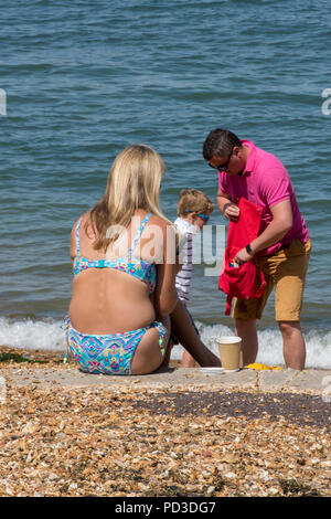 Cowes, Großbritannien. 6. August 2018. Die hohe tempertatures weiter und die Leute machen das Beste aus der heißen suuny Wetter in Cowes auf der Isle of Wight. Eine Familie am Strand und am Meer. Die Menschen in der Sonne beobachten die Segelyacht rennen und Zeit miteinander zu verbringen am Strand im heißen August Sonnenschein. Quelle: Steve Hawkins Fotografie/Alamy leben Nachrichten Stockfoto