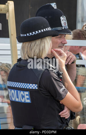 Cowes, Großbritannien. 6. August 2018. Die hohe tempertatures weiter und die Leute machen das Beste aus der heißen suuny Wetter in Cowes auf der Isle of Wight. Männliche und weibliche Polizisten auf Streife während einer Veranstaltung in Cowes auf der Isle of Wight. Die Menschen in der Sonne beobachten die Segelyacht rennen und Zeit miteinander zu verbringen am Strand im heißen August Sonnenschein. Quelle: Steve Hawkins Fotografie/Alamy leben Nachrichten Stockfoto