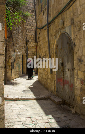 11. Mai 2018 Eine muslimische Frau in der traditionellen islamischen Kleidung zu Fuß einer schmalen Seitenstraße der Via Dolorosa in Jerusalem, Israel Stockfoto