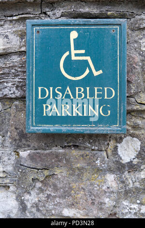 Behinderte Parken Schild mit gelber Text und der Mensch Person im Rollstuhl Symbol mit grünem Hintergrund auf einer alten Steinmauer Stockfoto