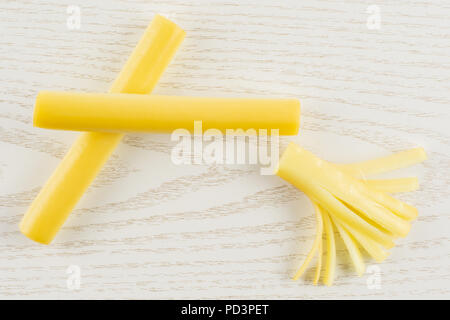 Gruppe von zwei ganzen ein Stück geräucherte slowakischen String Käse stick flatlay auf grau Holz Stockfoto