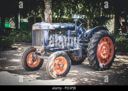 Ein rustikales Vintage blau Fordson Traktor mit verblasste rote Räder sitzt in dappled Schatten auf dem Parkplatz in Goodwood Rennstrecke Stockfoto