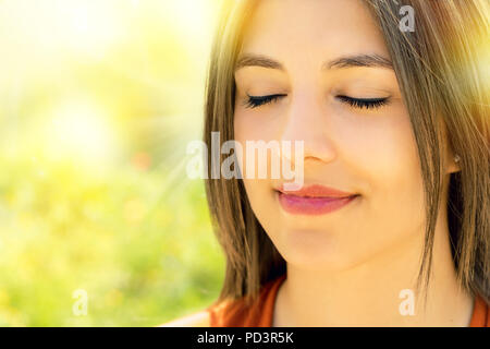 Close up Portrait von attraktiven entspannt junge Frau meditieren im Freien. Mädchen mit Augen gegen Farbenfrohe outdoor Hintergrund geschlossen. Stockfoto