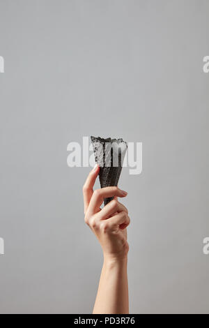 Frische leer schwarz Waffel Kegel in eine weibliche Hand auf einem grauen Hintergrund mit Kopie Raum Stockfoto