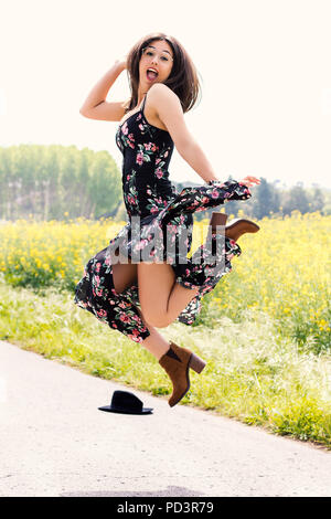 Volle Länge Aktion Portrait von jungen Mädchen in Flower dress springen im Freien. Stockfoto