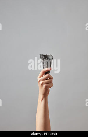 Schwarz Waffel Kegel in eine weibliche Hand auf einem grauen Hintergrund mit Kopie Platz für Ihren Text. Stockfoto
