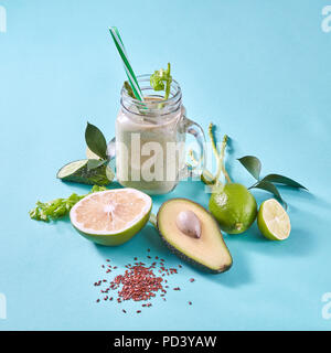 Hausgemachte grüne Smoothies mit Scheiben Zitrone, Limone, Avocado, selery, Gurke mit Leinsamen auf blauem Papier Hintergrund. Stockfoto