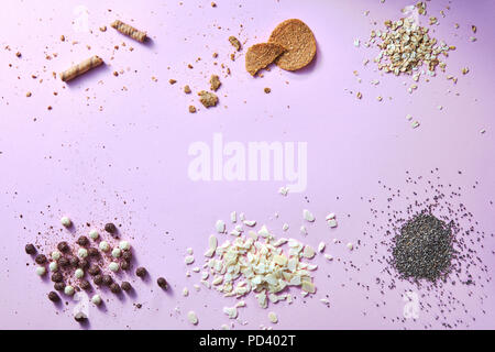 Flache lai Hintergrund aus verschiedenen Arten: wafer Croissants, Gebäck, Haferflocken, Müsli Kugeln, Mandelflocken und Mohn auf einem rosa Oberfläche Stockfoto