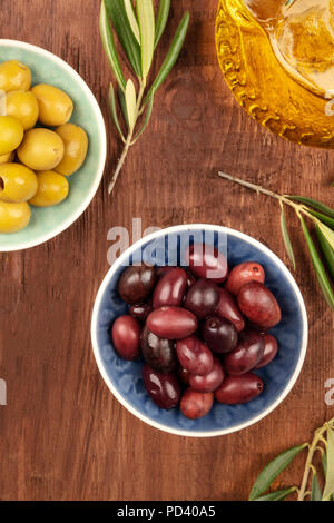 Ein Foto von verschiedenen Oliven in Schalen mit Blättern und kopieren Sie Raum, auf einem dunklen rustikalen Hintergrund Stockfoto