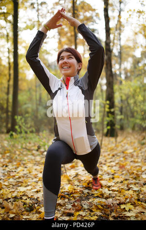 Herbst Foto der sportlichen Frau dehnen in Wald am Morgen gegen den Hintergrund der Bäume Stockfoto