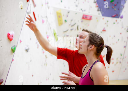 Foto der jungen Sportlerin und Mann auf Wand Hintergrund für Klettern Stockfoto