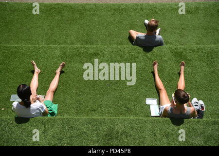 Sonnenanbeter auf den Stufen Getreidespeicher Square, King's Cross, London genießen Sie die weiterhin heißes Wetter. Stockfoto