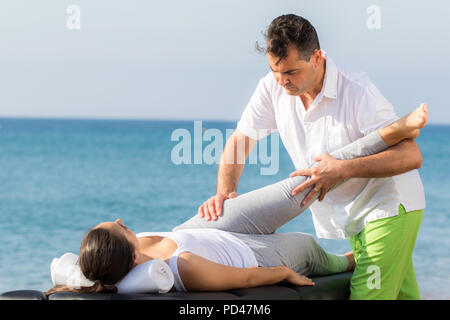 Nahaufnahme der männlichen Osteopath, Hüfte und Bein Behandlung im Freien auf weibliche Patienten. Stockfoto