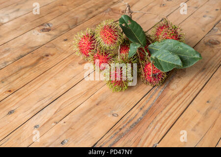 Roten rambutan Nephelium lappaceum auf broun Board. Obst tropischen Baum der Familie Sapindaceae, beheimatet in Südostasien, in vielen Ländern angebaut Stockfoto